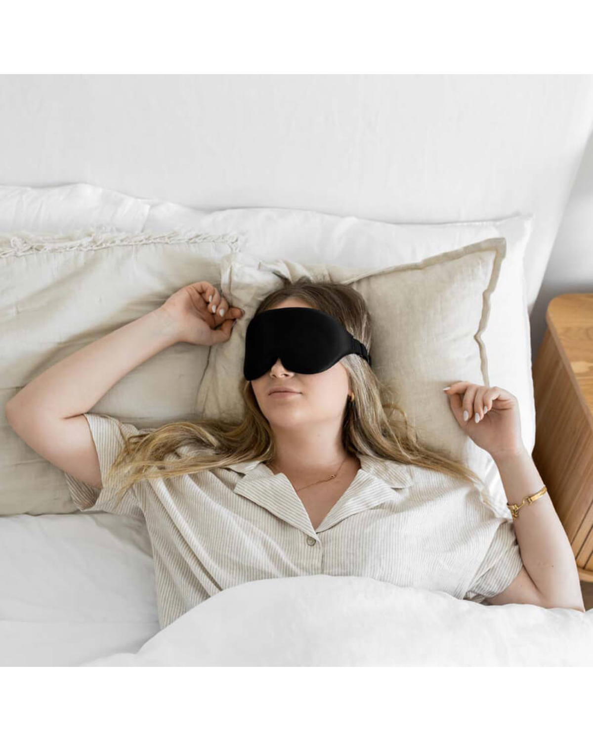 Woman resting on her back wearing a black sleep mask
