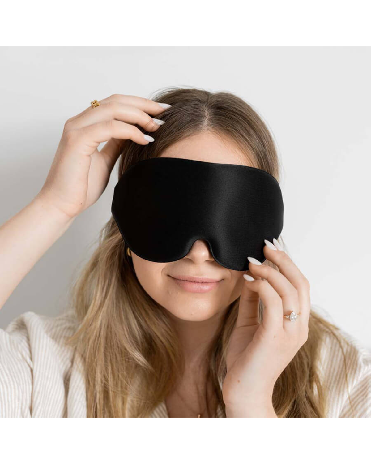 Front view of a black sleep mask being adjusted