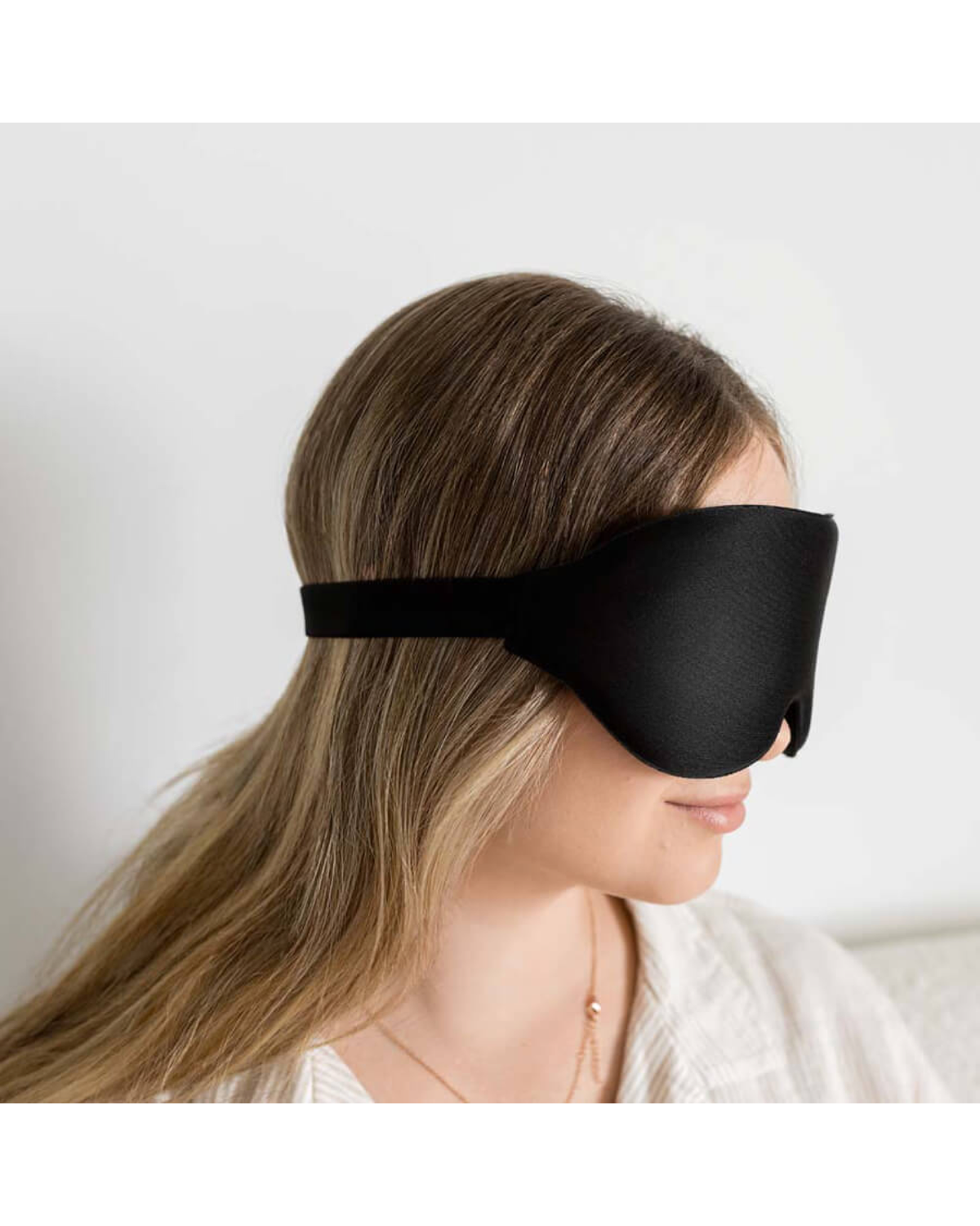 Side view showing the black sleep mask and strap