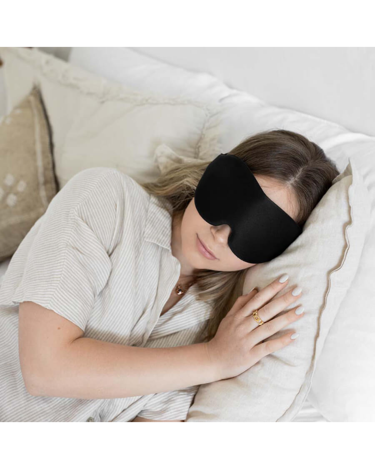 Woman sleeping on her side wearing a black sleep mask